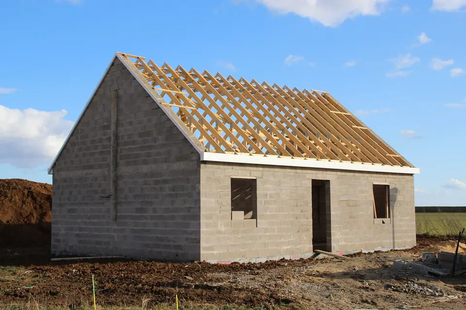 Maison individuelle en construction avec sa charpente en bois posée, avant la couverture.